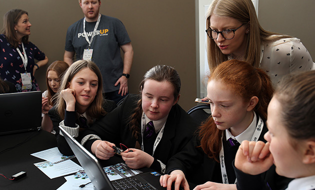 School girls round laptop being instructed by adult at Women in Data Science event