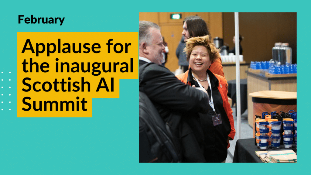 Image of Steph Wright from the Scottish AI Alliance laughing with a visitor at their DataFest stand. Steph has short, spikey hair and is wearing a bright orange suit to match the AI Alliance logo. Overlay text reads "Applause for the inaugural Scottish AI Simmit"
