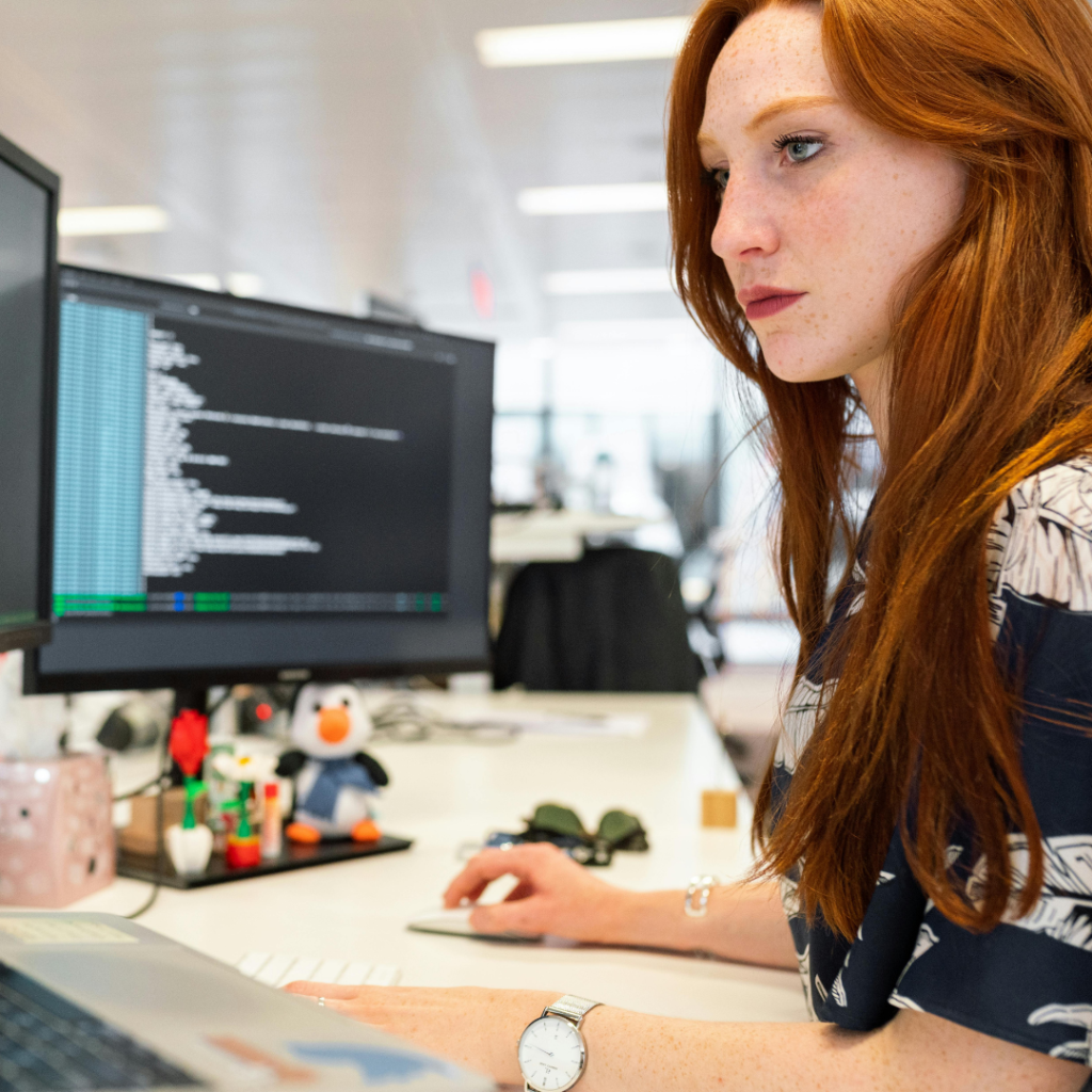 Woman at desk in front of laptop and monitors