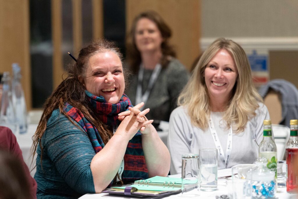 Two women smiling seated at a table during a workshop