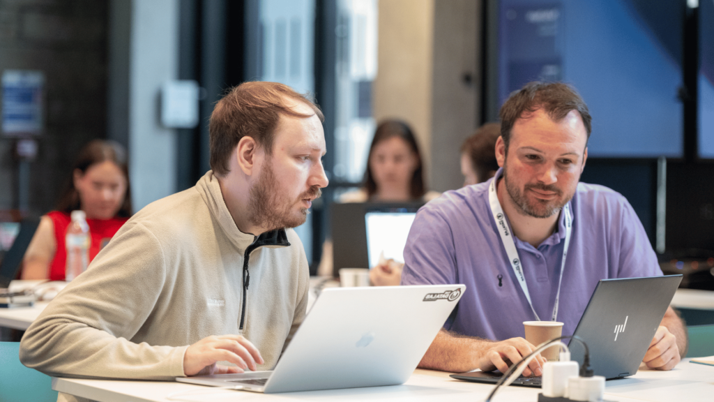 Two men sitting at their laptops working together